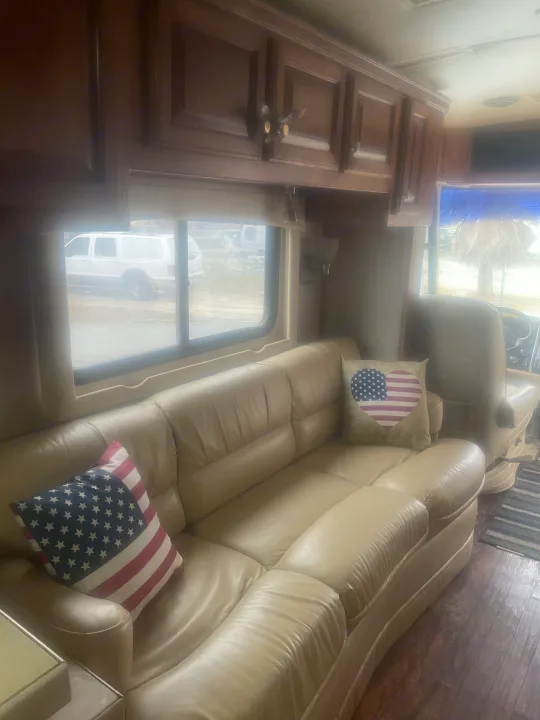Cozy RV rental interior with a comfy light-colored sofa, patriotic pillows, and a hidden cat peeking from cabinets. Perfect for travel!. Airstream Skydeck 2008