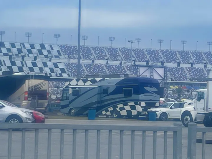 A large, checkered RV sits near stadium grandstands, reminiscent of racing events. Consider an RV rental for trackside spectating.. Airstream Skydeck 2008