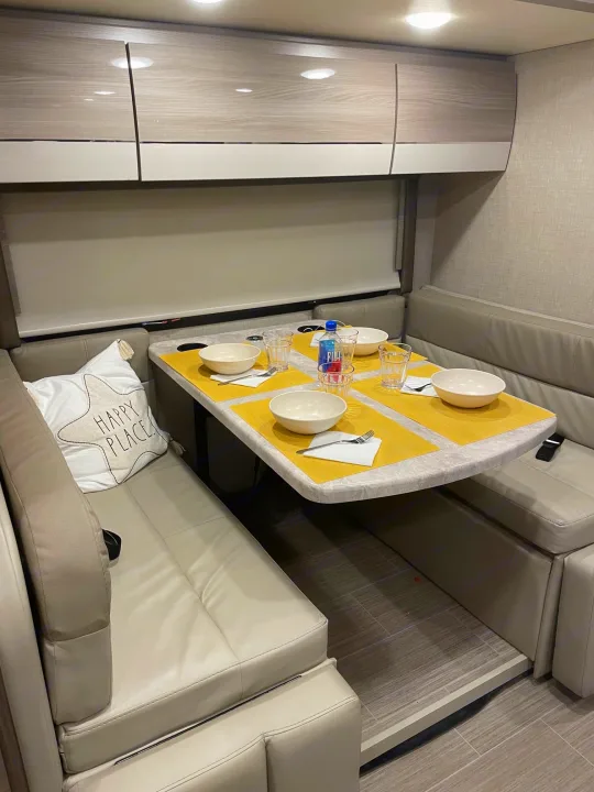 Cozy RV rental dinette interior with comfortable seating and a set table, perfect for meals on the road.. Mercedes Delano Sprinter 2022