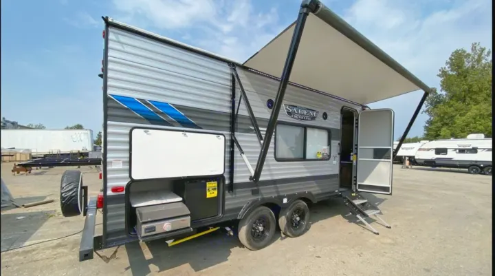 A gray & black Salem Cruise Lite travel trailer is displayed, featuring an extended awning & outdoor kitchen. Great for rv rental.. Forest River Salem Cruise Lite 2022