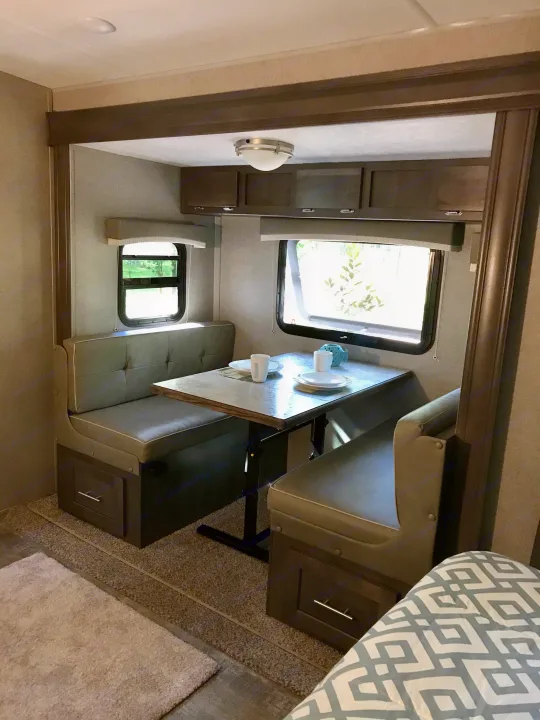 Cozy RV rental dinette area with table set for meals, perfect for travel & relaxation.. Forest River Rockwood Mini Lite 2020