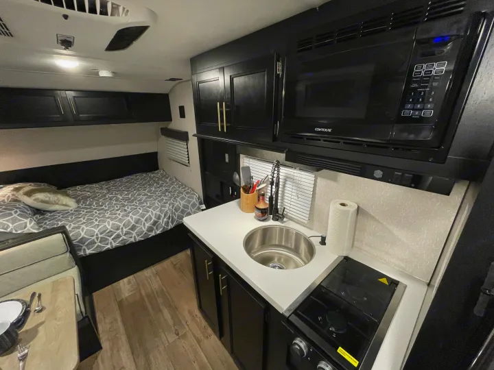 This rv rental offers a comfy bed, compact kitchen with microwave & stove, and dining nook, all in a modern black and white interior.. Forest River Cherokee Wolf Pup Black Label 2022
