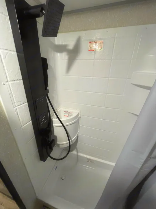 Modern black shower panel, rain head, and small corner basin in a clean RV rental shower.. Forest River Cherokee Wolf Pup Black Label 2022