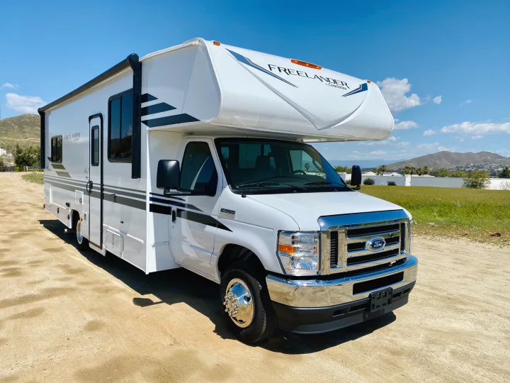 White Coachmen Freelander Class C RV rental parked on a dirt path under a clear sky, ready for adventure.. Coachmen Freelander 2021