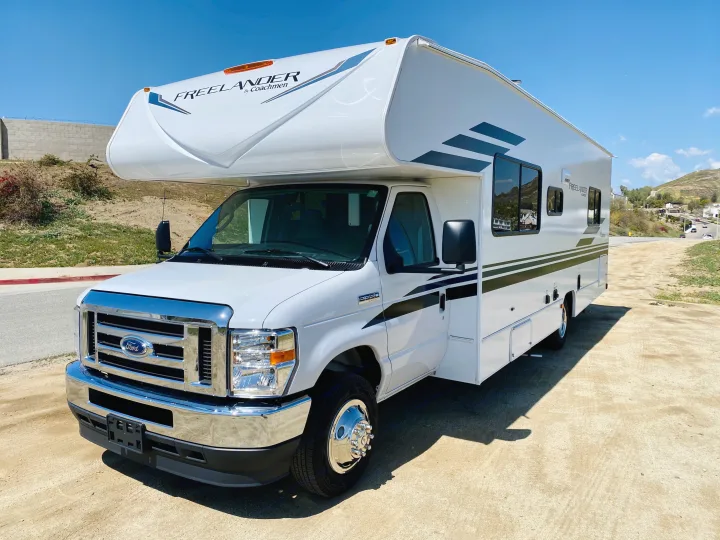 White Coachmen Freelander RV rental, a Class C motorhome on a Ford chassis, parked on a dirt lot.. Coachmen Freelander 2021