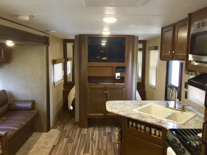 Spacious RV rental interior featuring a modern kitchen, living area with sofa & TV, and accessible bedrooms. Ideal for travel.. Keystone Hideout 2018