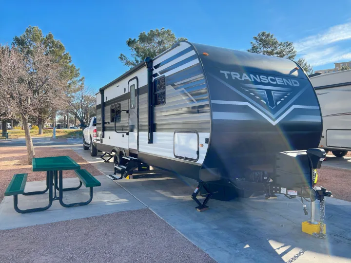 This **rv rental** travel trailer is parked at a sunny campground site with a green picnic table nearby.. Grand Design Transcend Xplor 240BH 2022