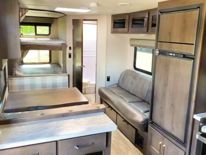 Inside this RV rental: bunk beds, dinette, kitchen area, fridge, sofa, and a bathroom. Perfect for travel adventures!. Grand Design Transcend Xplor 240BH 2022