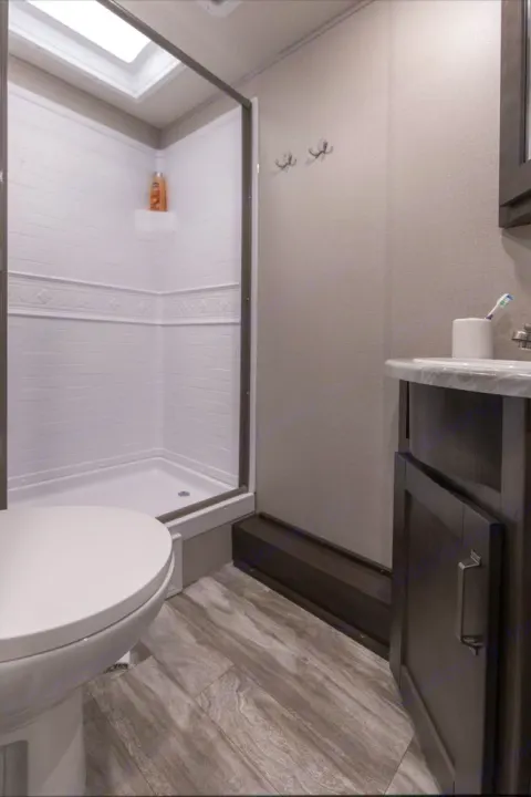 Clean RV rental bathroom featuring a shower, toilet, vanity, and modern decor. Perfect for your next trip.. Grand Design Transcend Xplor 240BH 2022