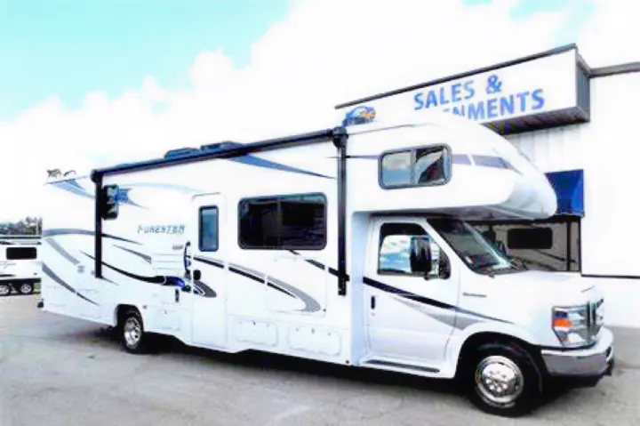 White Forester Class C motorhome parked outside a sales building, available for RV rental.. Forest River Forester 2020