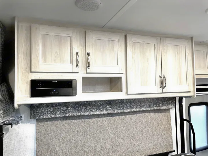 Clean RV rental interior with light overhead cabinets, an integrated Connex media center, and a patterned window shade.. Forest River Forester 2020