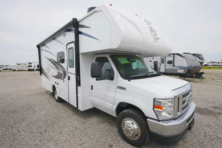 A white Triumph Class C motorhome, possibly an rv rental, is parked on a gravel lot with other RVs in the background.. Nexus Triumph 2022