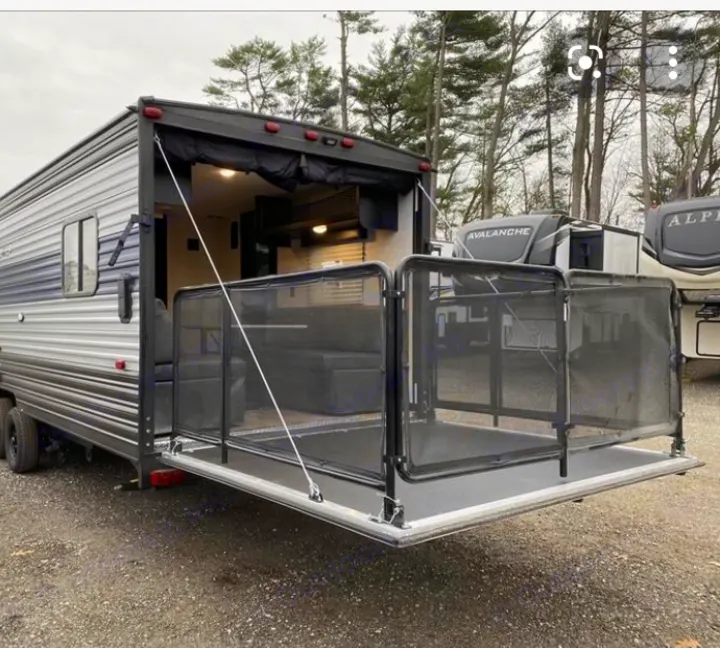 Explore this toy hauler RV rental, showcasing its rear ramp patio deck with protective mesh railings and versatile interior seating.. Forest River Cherokee 2021