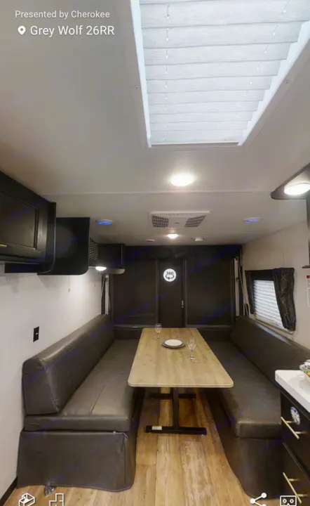 RV rental interior: spacious dinette with dark benches, wood table, and bright skylight. Ideal camper/travel trailer for trips.. Forest River Cherokee 2021