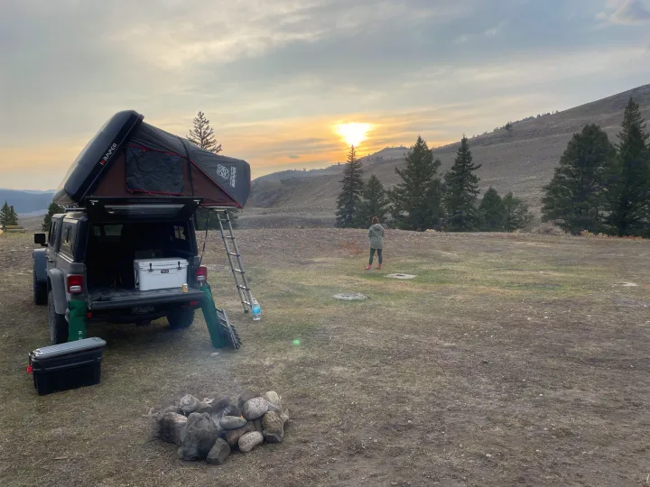 Adventure-ready truck with rooftop tent and campfire at sunset, perfect for an outdoor RV rental experience.. Jeep Gladiator Unlimited 2020