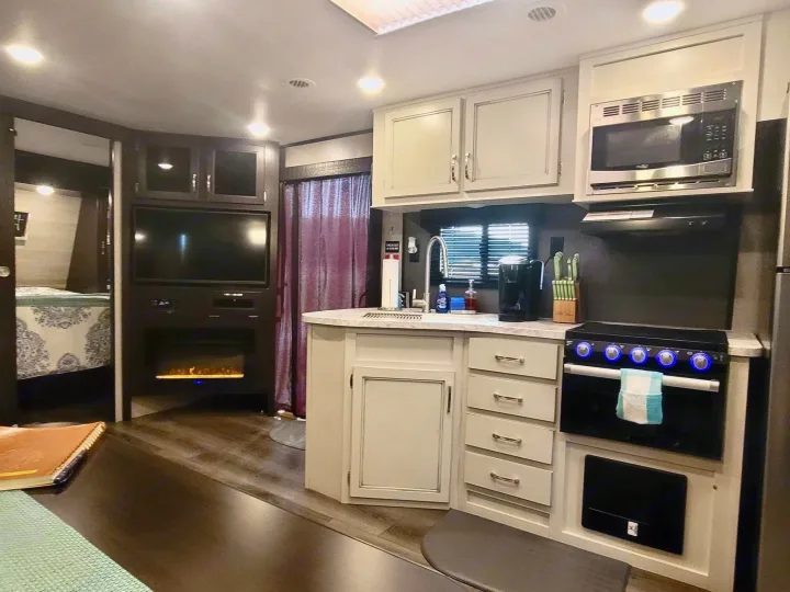 Spacious RV rental interior featuring a modern kitchen, living area with TV and fireplace, and a glimpse of the bedroom.. Jayco Jay Flight 2022