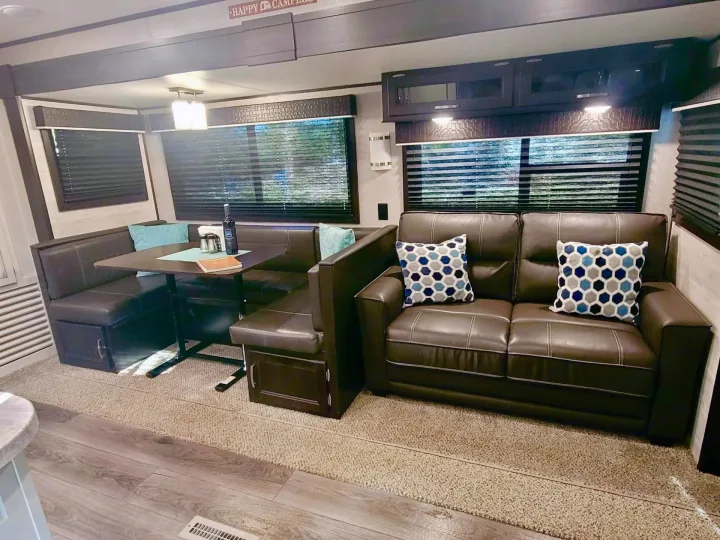 Spacious RV rental interior featuring a cozy dinette, comfortable sofa with throw pillows, and overhead storage.. Jayco Jay Flight 2022