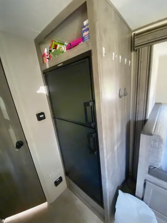 RV rental interior showing a countertop with hooks, a Dometic mini-fridge, and side storage.. Coachmen Apex Nano 194 BHS 2021