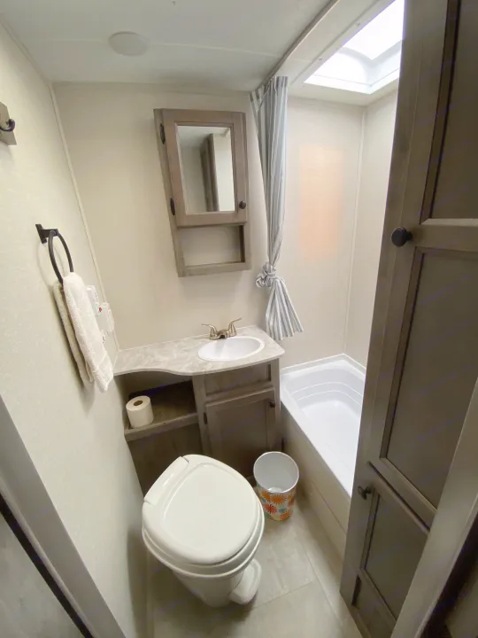 Compact RV rental bathroom with a toilet, sink vanity, medicine cabinet, and shower/tub combo with a skylight.. Coachmen Apex Nano 194 BHS 2021