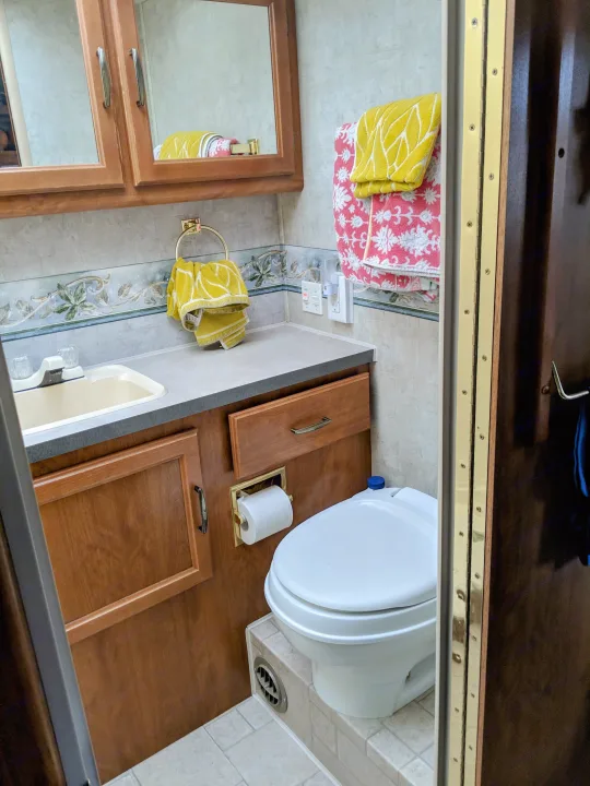 RV rental bathroom: Compact and functional with sink, toilet, and storage, ready for your travel needs.. Fleetwood Tioga 2005