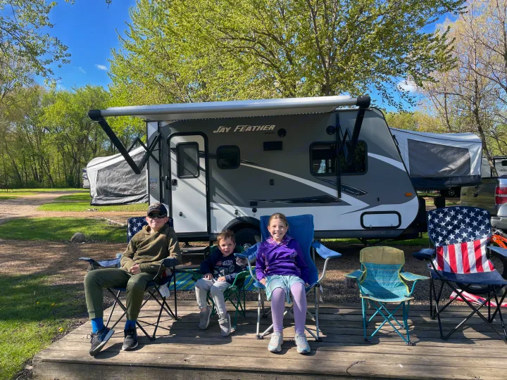 Kids relax on a deck by their Jay Feather RV rental at a sunny campground, enjoying outdoor family fun.. Jayco Jay Feather 2016