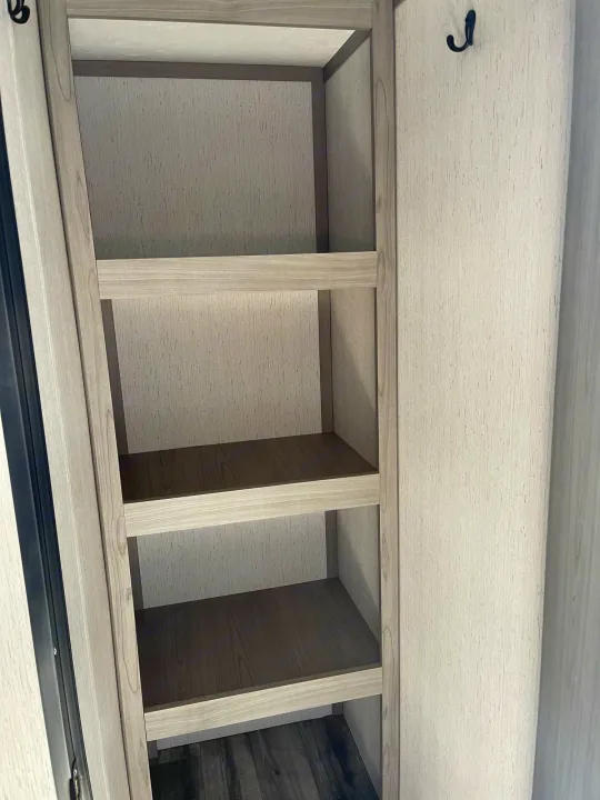 RV rental interior featuring organized light wood shelves and a coat hook. Ideal storage for your travel essentials.. Dutchmen Coleman 2022