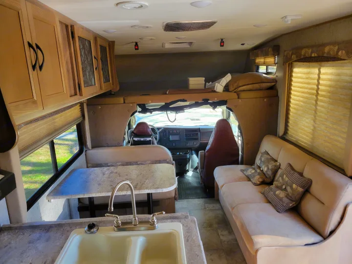 Inside an RV rental: cozy living space with kitchen, dinette, sofa, and overhead bunk area.. Coachmen Freelander 2017