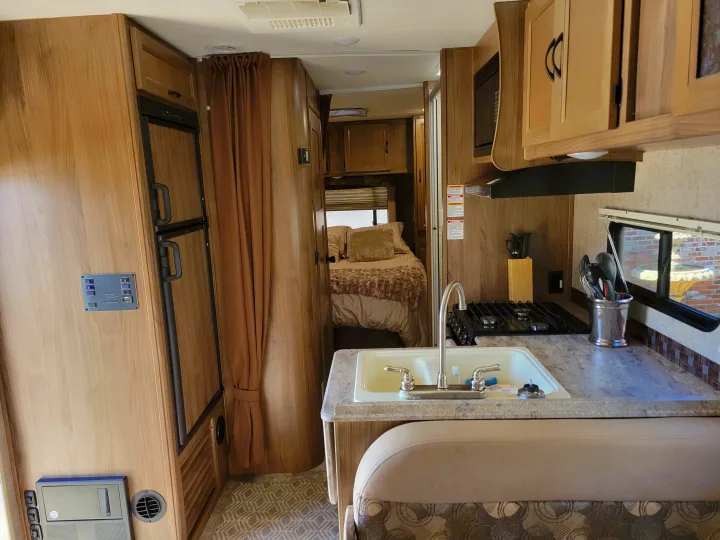 An RV rental interior showing a functional kitchen, dinette, and comfortable bed beyond for your next adventure.. Coachmen Freelander 2017