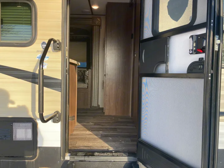 Experience RV rental comfort: open door view of interior with wood floor, patterned dinette, and exterior details.. Keystone Hideout 2019