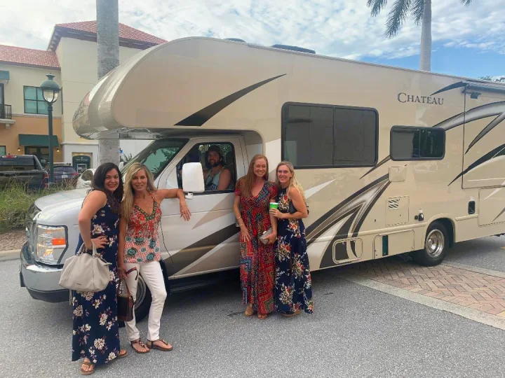 Friends enjoying their RV rental adventure. Four women and a man pose cheerfully with a beige Chateau motorhome, parked outdoors on a sunny day.. Thor Motor Coach Chateau 2020