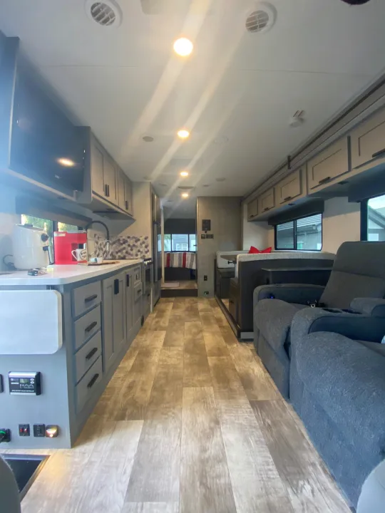 Spacious RV rental interior featuring a modern kitchen, dining area, recliners, and a bedroom beyond.. Forest River Solera 2022