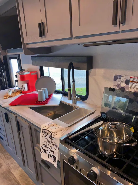 This rv rental features a compact, fully equipped kitchen with a sink, stovetop, and coffee maker, perfect for camping.. Forest River Solera 2022