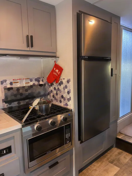 RV rental kitchen with compact stainless steel stove, microwave, and refrigerator. Ideal for travel.. Forest River Solera 2022