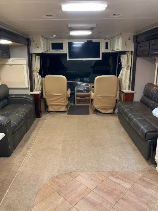 Explore this inviting RV rental interior, showcasing the cockpit, comfy sofas, and overhead entertainment.. Monaco Windsor 2004