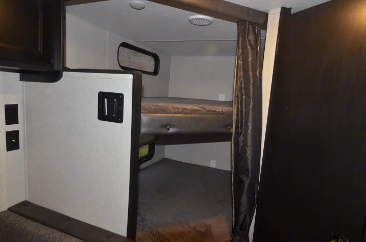 RV rental interior: Cozy bunk beds with window and TV mount, ideal for family adventures in a compact RV.. Forest River Cherokee 2021