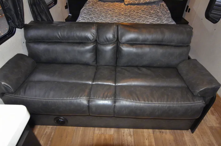 This inviting dark gray sofa with white stitching, complete with an air vent, offers comfort in an RV rental interior.. Forest River Cherokee 2021
