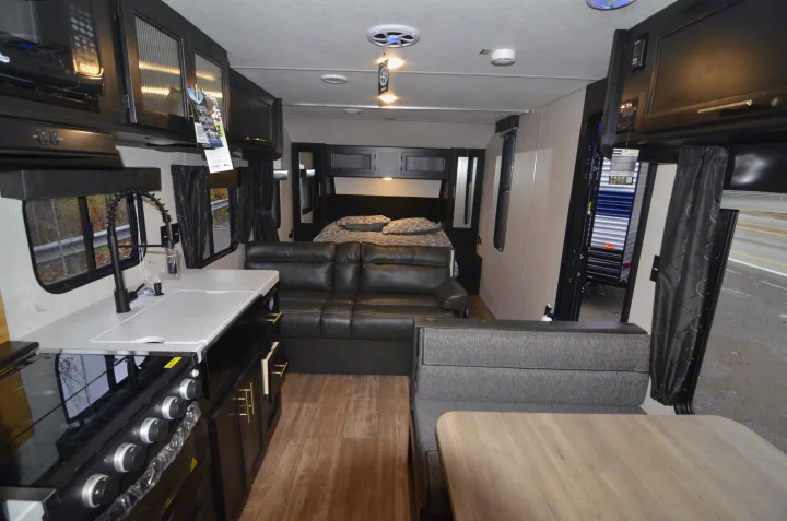 Spacious RV rental interior with kitchen, living area, and bedroom, featuring modern dark and light decor.. Forest River Cherokee 2021