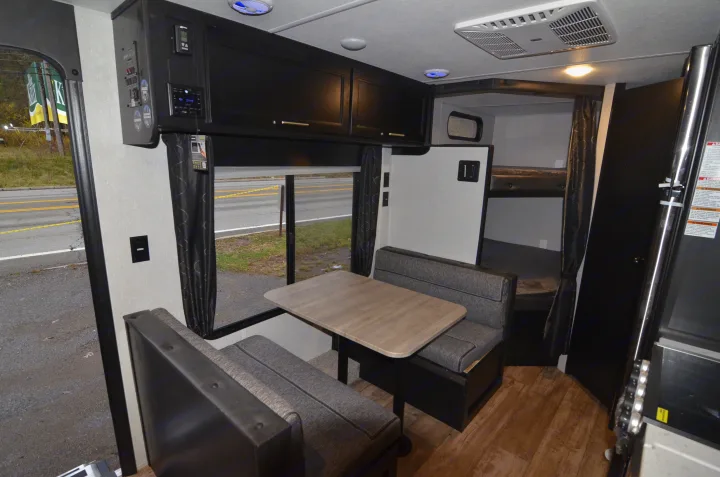 RV rental's inviting interior shows a dinette with bench seating, overhead cabinets, and bunk beds, ready for your journey.. Forest River Cherokee 2021