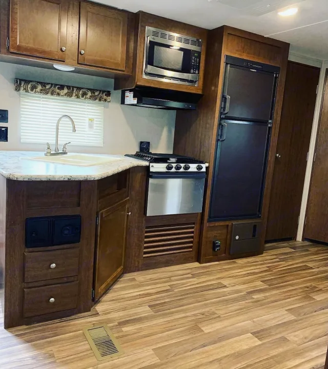 Explore this functional RV rental kitchen, featuring a sink, microwave, stove, and refrigerator. Your home on wheels awaits!. Keystone Hideout 2018