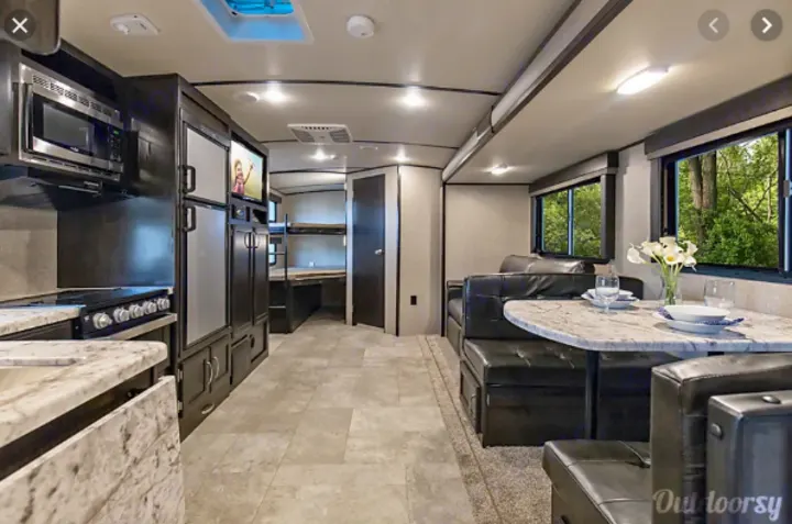 Spacious rv rental interior with kitchen, dining area, and bunk beds, perfect for family adventures.. Grand Design Imagine 2800BH 2019