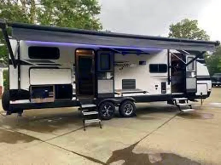 This spacious white travel trailer RV with extended awning & open doors is perfect for your next RV rental adventure.. Grand Design Imagine 2800BH 2019