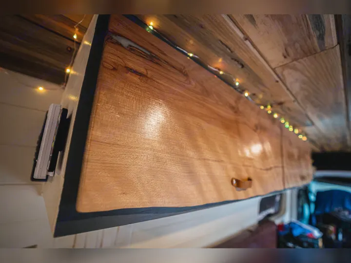 Cozy RV rental interior: wooden overhead cabinets, ambient string lights, and convenient remote storage.. Dodge promaster 3500 2018