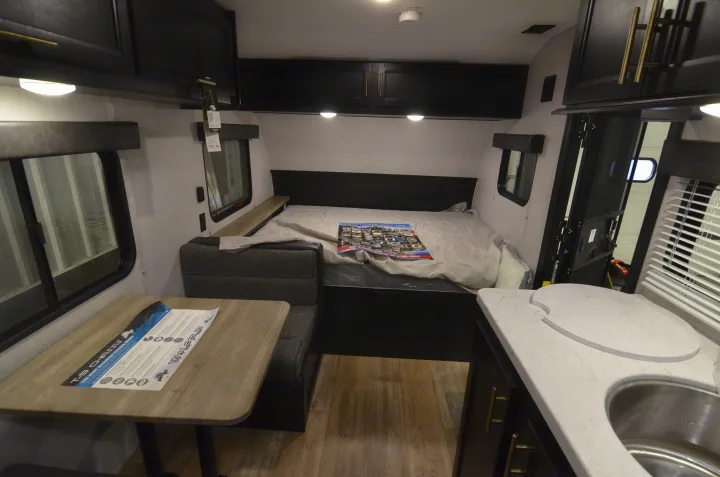 Explore this inviting RV rental interior, showcasing a comfortable bed, compact dinette, and functional kitchen with sink.. Forest River Cherokee 2021