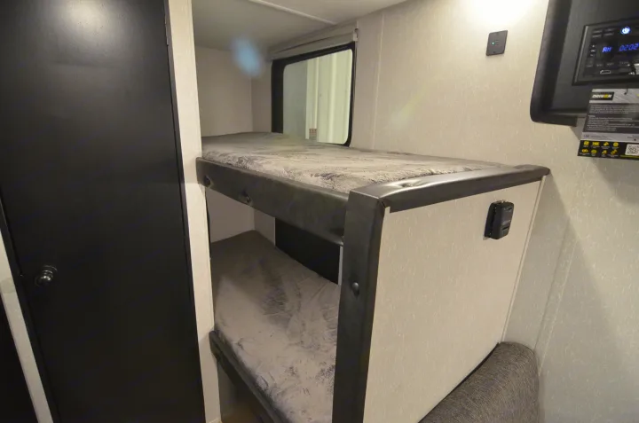 This rv rental features compact bunk beds, offering a cozy sleeping area inside a travel trailer.. Forest River Cherokee 2021