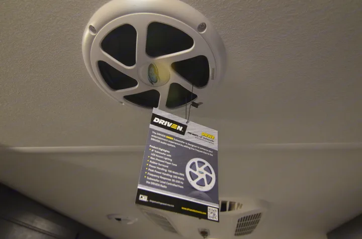 White ceiling-mounted DRIVEN speaker/subwoofer with an info tag, perfect for an RV rental's audio system.. Forest River Cherokee 2021