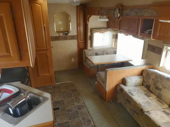 RV rental interior: A bright, cozy space featuring a kitchen sink, dining booth with table, and a comfortable patterned sofa.. Forest River Wildcat 2008
