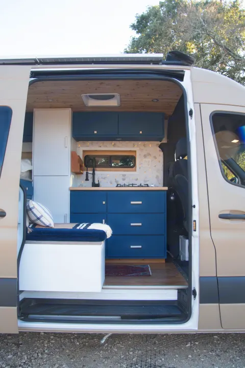 Stylish rv rental camper van interior: custom blue kitchen, cozy bench, wood ceiling, solar panels.. Mercedes-Benz Sprinter 2021