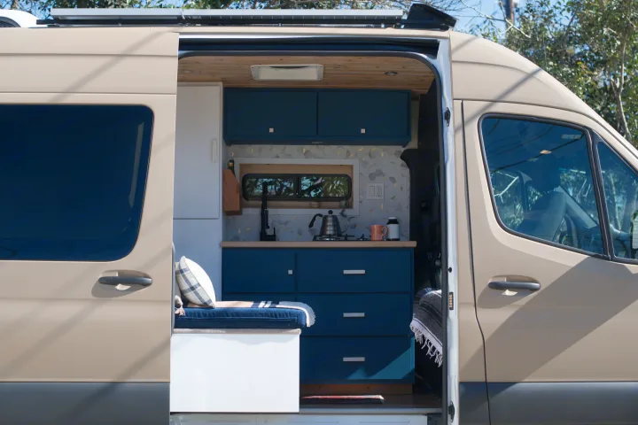 Step inside this stylish RV rental! Features a modern kitchen, cozy bench, and custom wood accents for your next adventure.. Mercedes-Benz Sprinter 2021