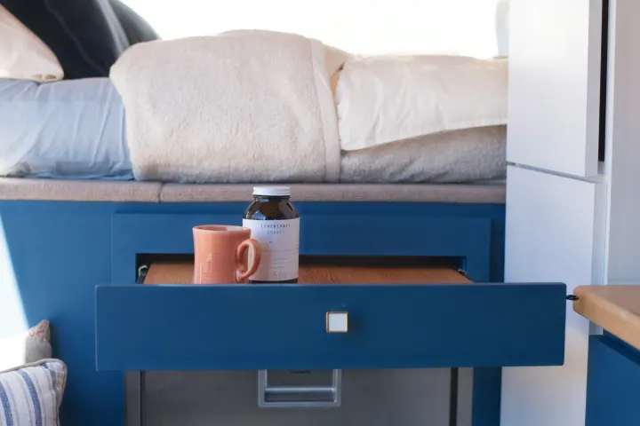 This rv rental features a cozy bed, smart blue cabinetry, and a pull-out shelf for amenities like coffee.. Mercedes-Benz Sprinter 2021