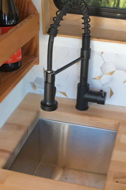 RV rental kitchen: black modern faucet, stainless sink, butcher block counter, and hexagon backsplash.. Mercedes-Benz Sprinter 2021